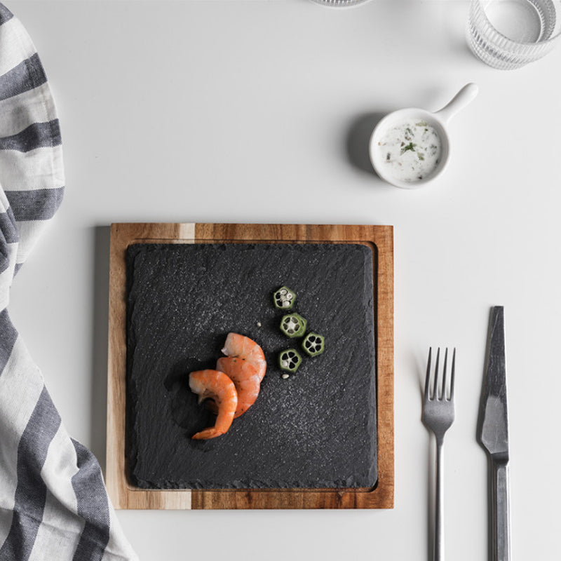 Handmade 14-inch oval acacia wood serving board on a kitchen table.