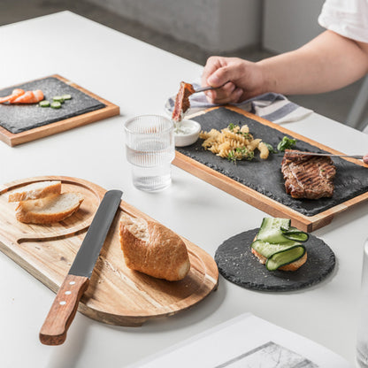 Handmade 14-inch oval acacia wood serving board on a kitchen table.