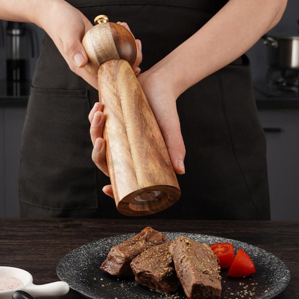 Compact 5-inch natural wood salt grinder displayed with fresh seasonings.